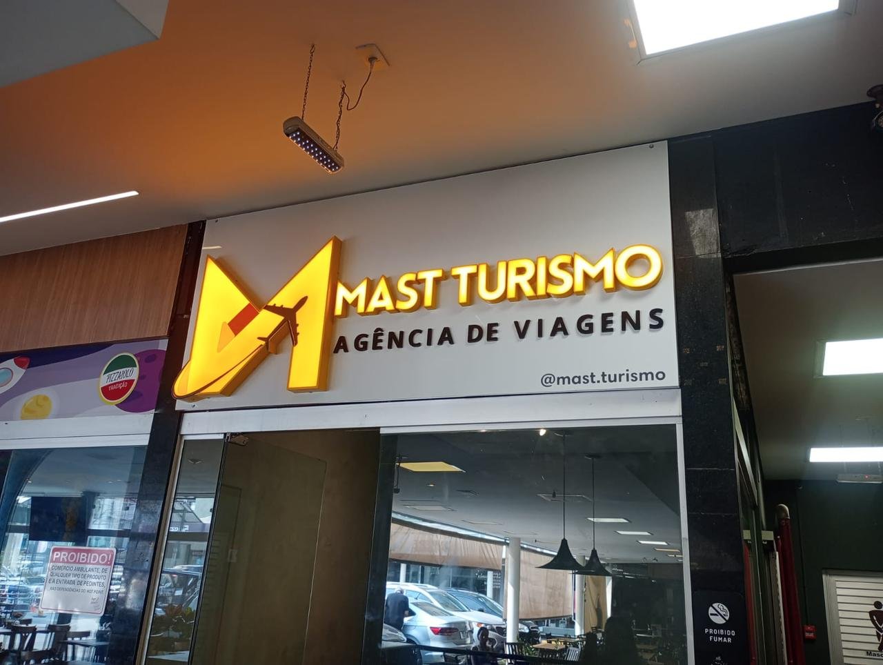 Fachada noturna da Macromaq iluminada em amarelo com marca preta em alto contraste.