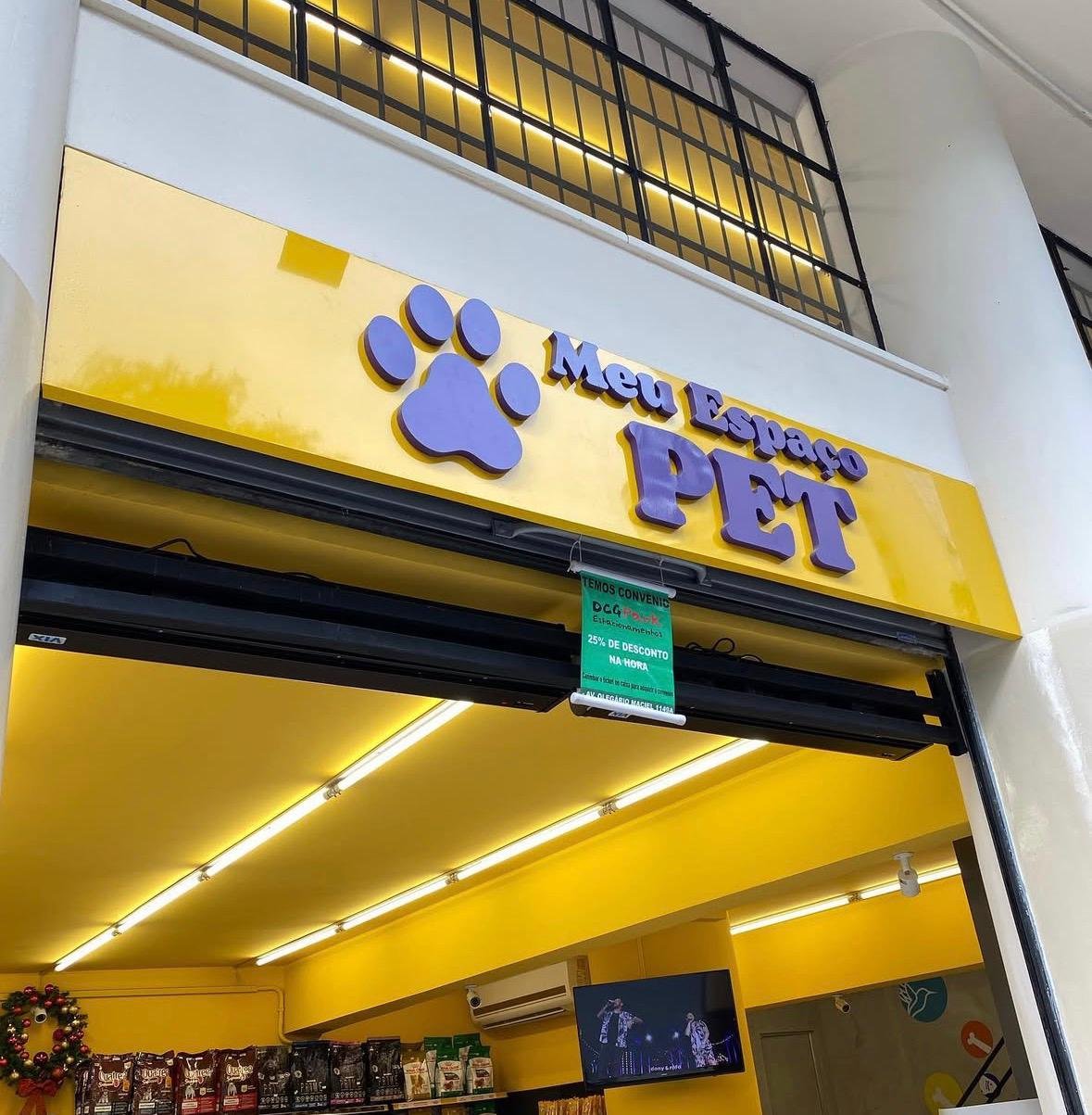 Fachada Meu Espaço Pet com painel amarelo e letras roxas em ambiente comercial.