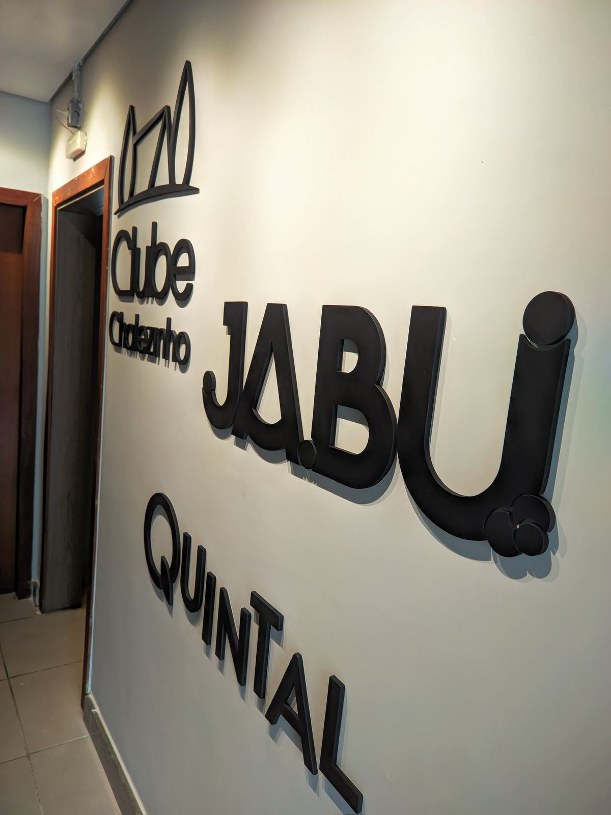 Composição interna em relevo com Clube Chalezinho, Jabui e Quintal aplicada em parede iluminada.