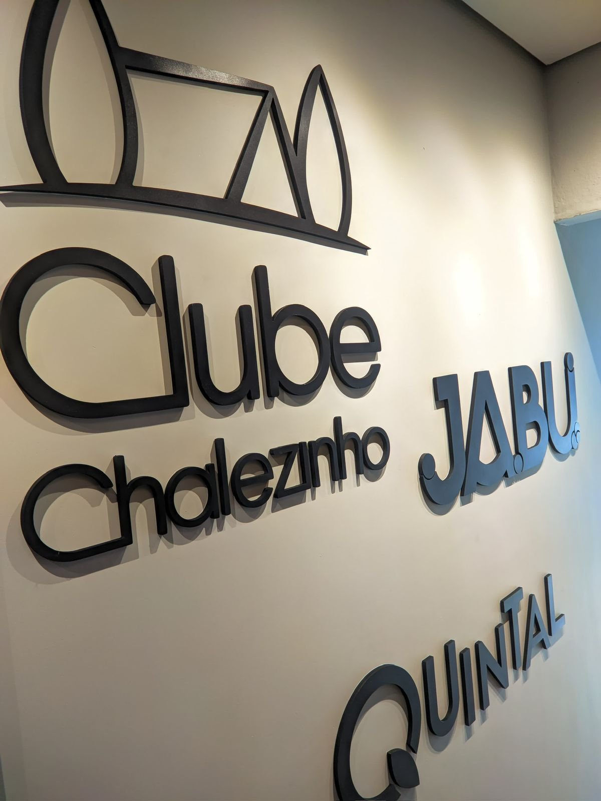 Vista aproximada dos letreiros Clube Chalezinho, Jabui e Quintal com profundidade e sombra lateral.