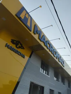 Miniatura: Fachada da Macromaq com identidade amarela e tipografia em destaque vista em perspectiva.