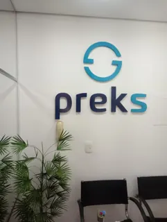 Miniatura: Logo e nome da Preks aplicados em parede interna com letras azuis e símbolo circular.