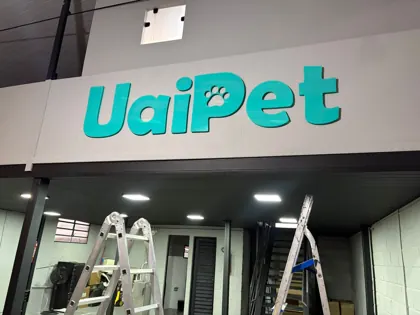 Miniatura: Letreiro externo da UaiPet em azul turquesa instalado em estrutura interna durante a montagem.